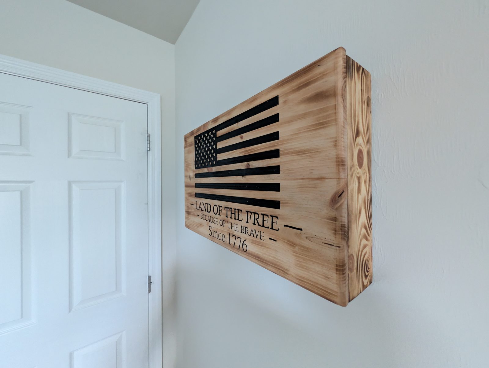 Hand-carved cabinet mounted on wall — American flag design with Land of the Free carving